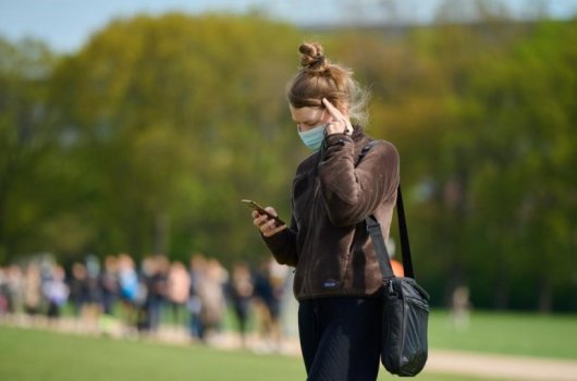 Woman with a face mask holding a cellphone