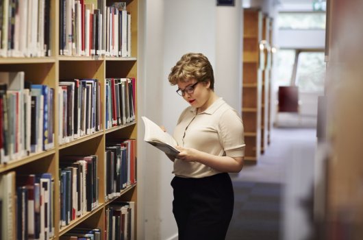 A woman reading a book in a library.
