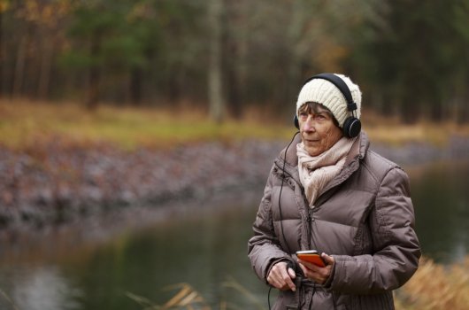 Woman walking in nature listening to music in headphones 