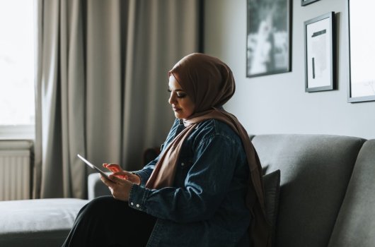Woman sitting in a sofa holding an IPad 