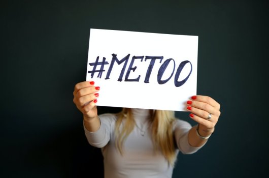 A woman holding a sign with the text "#metoo".