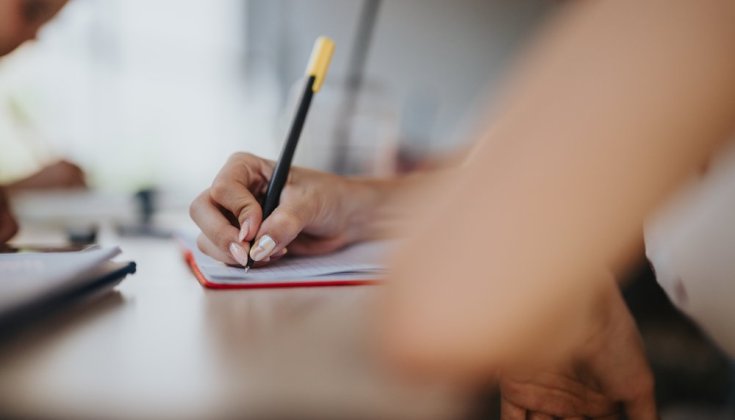 hand som skriver i ett anteckningsblock 